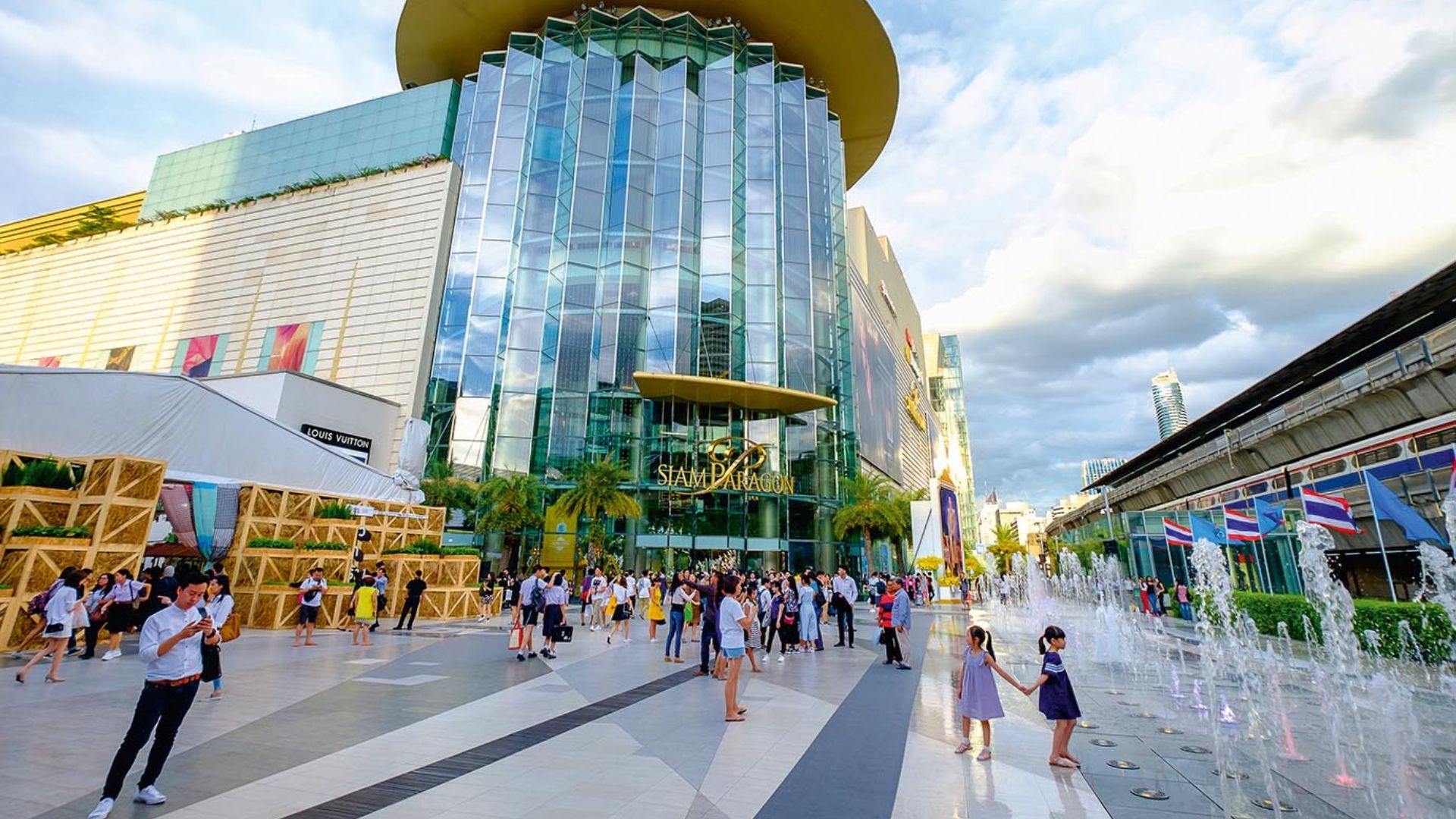 People walk past a Louis Vuitton store at Siam Paragon shopping