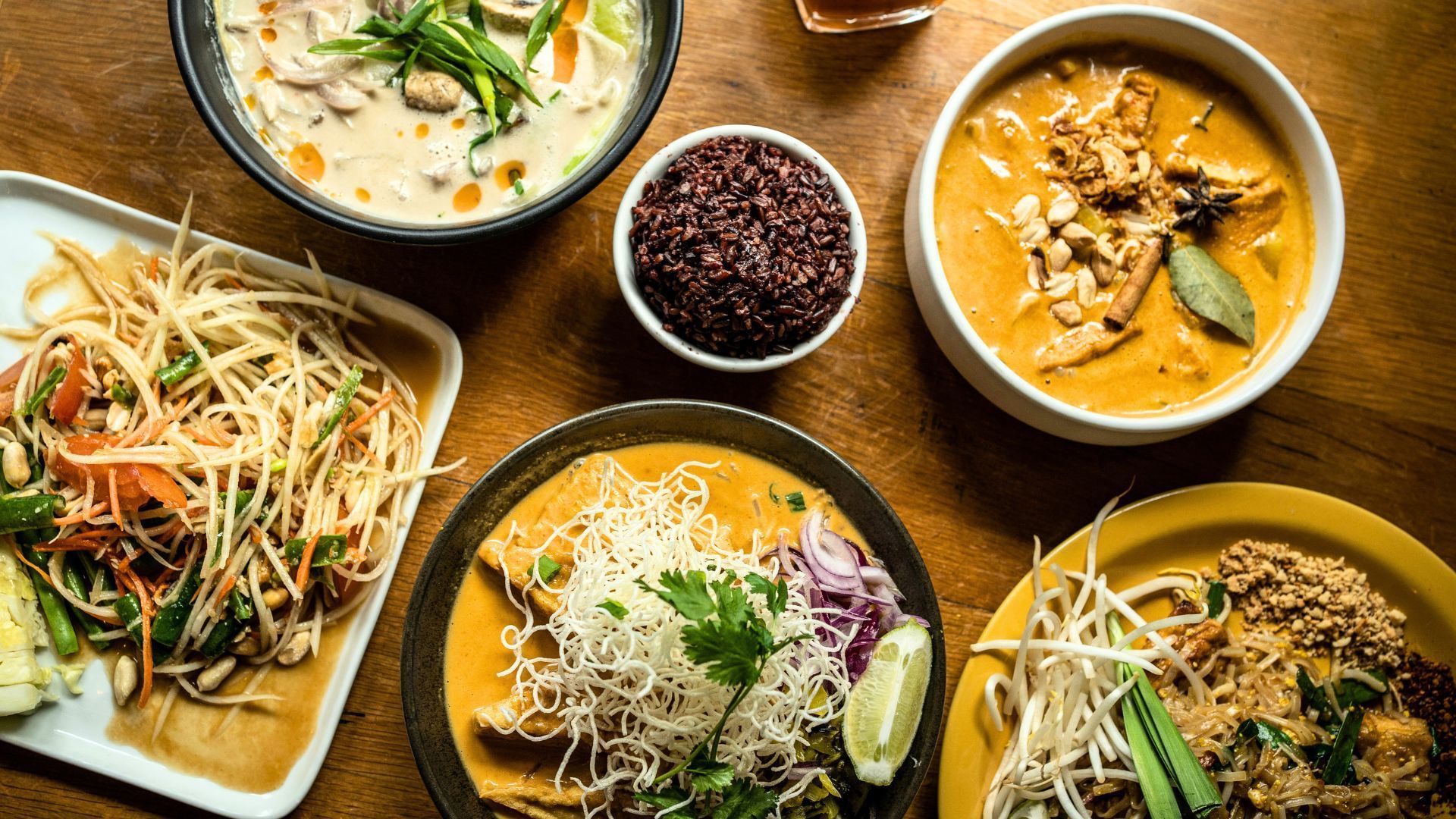 A spread of Thai curries, soups, stir-fries, noodles, and salads in a restaurant